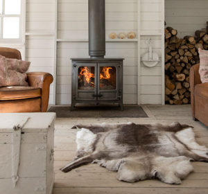 poêle à bois Island 3 sur pieds bas de couleur noir de la marque Charnwood en situation dans le salon d'une maison