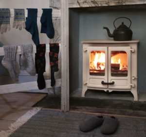 poêle à bois Island 2 ivoire sur pieds bas de couleur gris de la marque Charnwood en situation dans un salon d'une maison