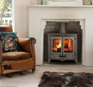 poêle à bois Island 2 sur pieds bas de couleur gris de la marque Charnwood en situation dans une cheminée